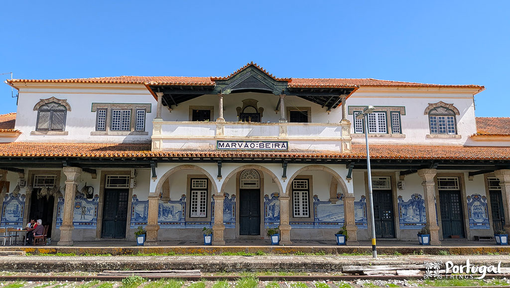 A histórica estação de trem de Marvão-Beirã, em Portugal, com a tradicional arte em azulejo, janelas e portas em arco e um telhado de azulejos sob um céu azul claro, é um local imperdível para quem quer explorar marvão o que visitar.