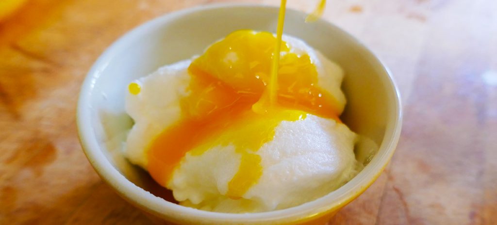 uma taça com claras em castelo cozidas cobertas por um molho amarelo de doce de ovos