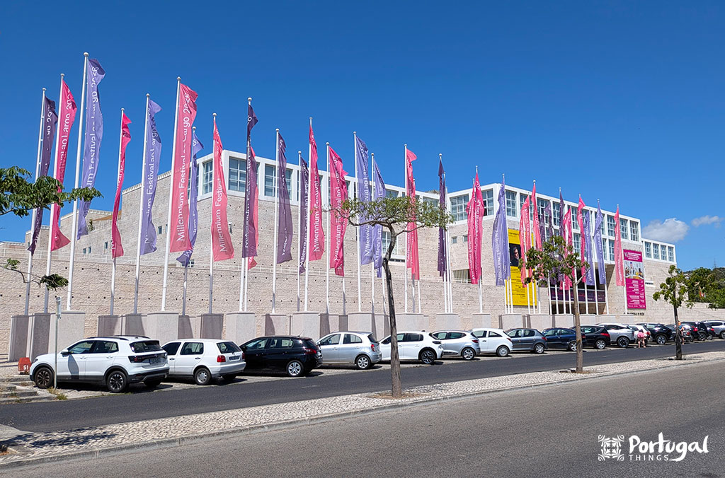 18 best things to do in Lisbon in 3 days - Itinerary 14 The Contemporary Art Museum building, with several flags in front and cars parked outside.