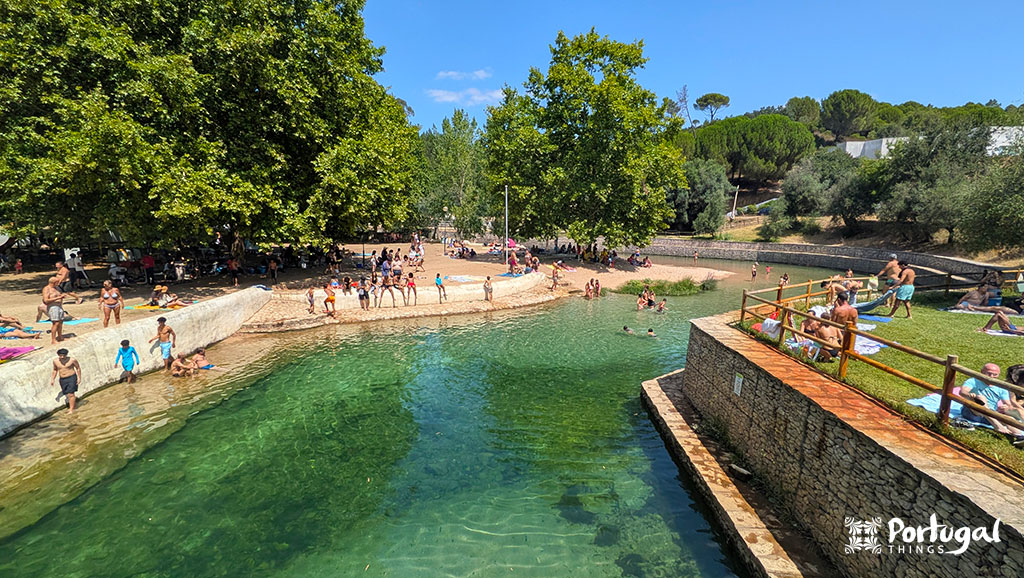Olhos de Água river beach with turquoise water and grassy areas for sunbathing.