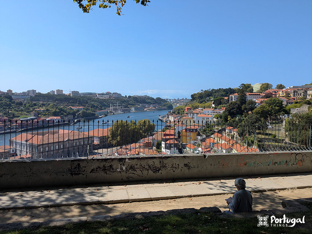 uma senhora a ler no miradouro das virtudes com o rio douro e a ponte de Arrábida no cenário
