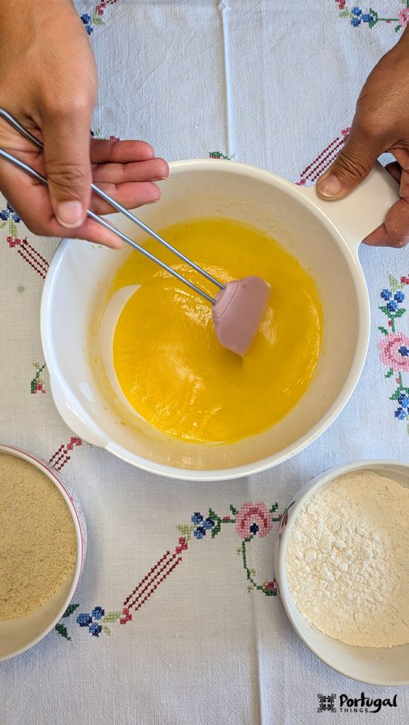 A hand stirs a bowl containing the almond tart batter.