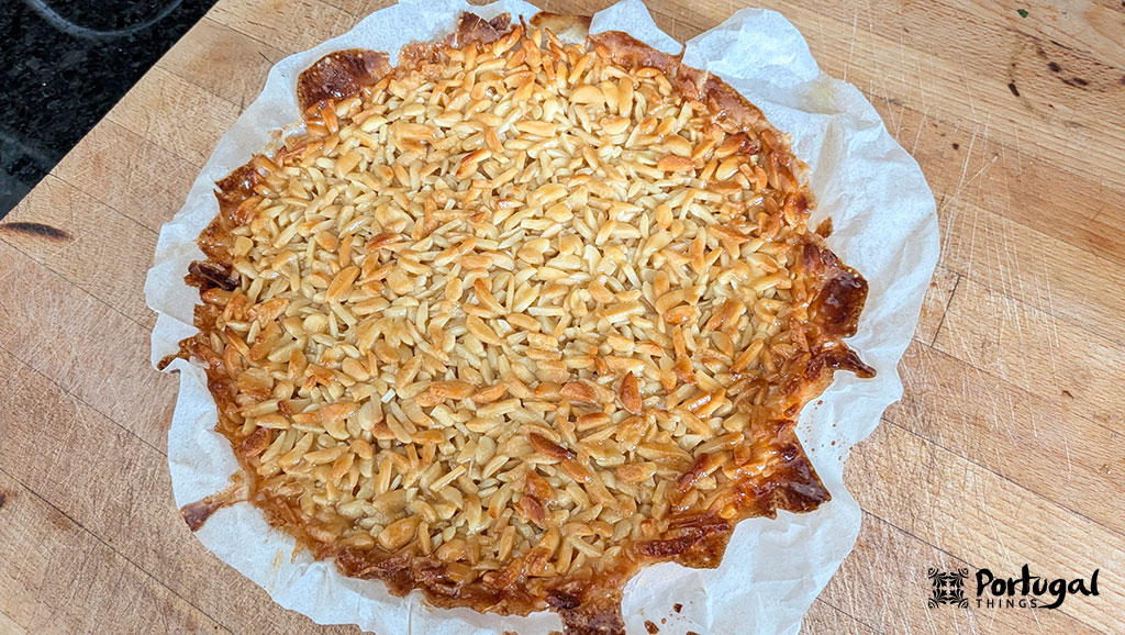 An almond tart, still in its pan, resting on a wooden board.