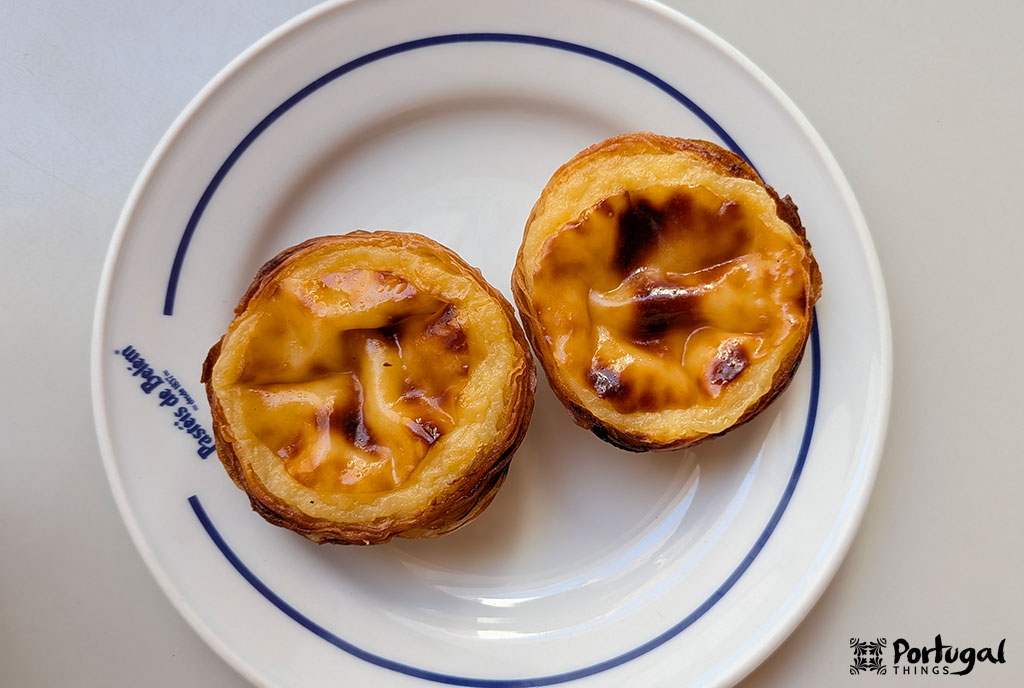 Two lightly caramelized Pastéis de Belém on a white plate