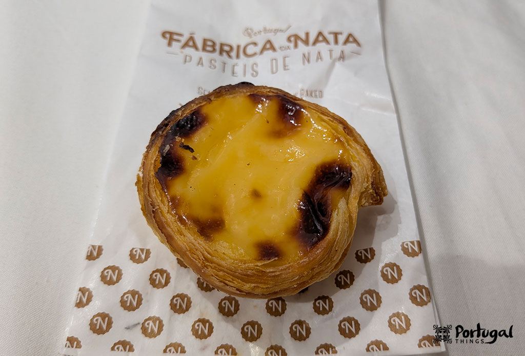 Lightly caramelized pastel de nata on Fábrica da Nata branded paper in Lisbon