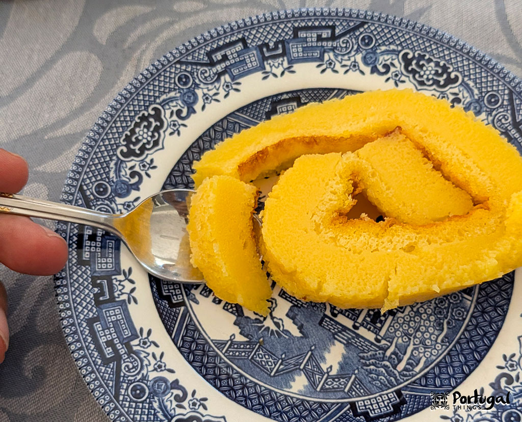A slice of orange pie on a blue plate and a spoon ready to serve.
