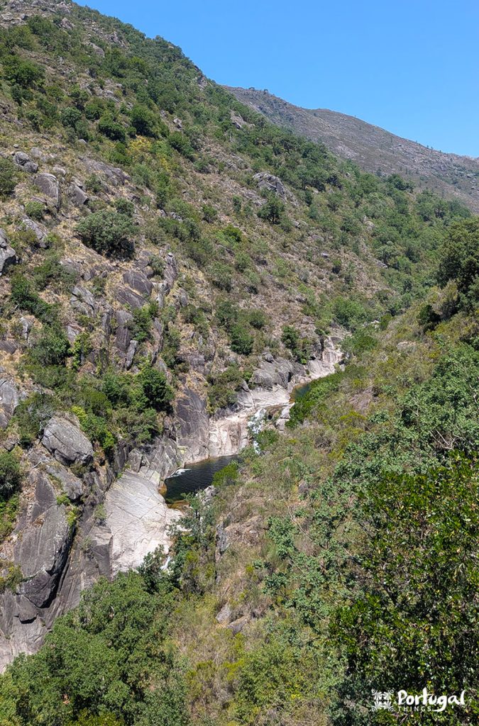 Varias cascatas e poças num desfiladeiro rodeado por arvores e montanhas