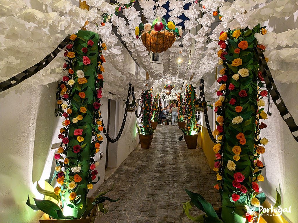 Rua com flores de papel especialmente rosas e flores brancas é de noite e tudo está iluminado