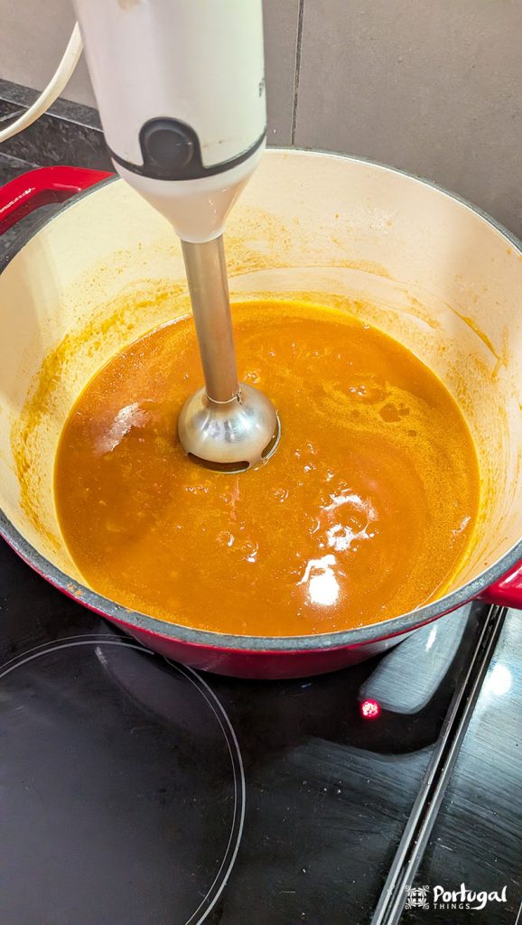An immersion blender blending the sauce until smooth and lump-free.