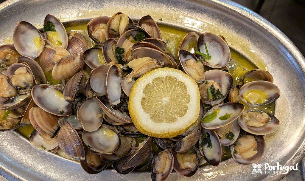 uma travesa com amêijoas e um molho por cima tem fatias de limão