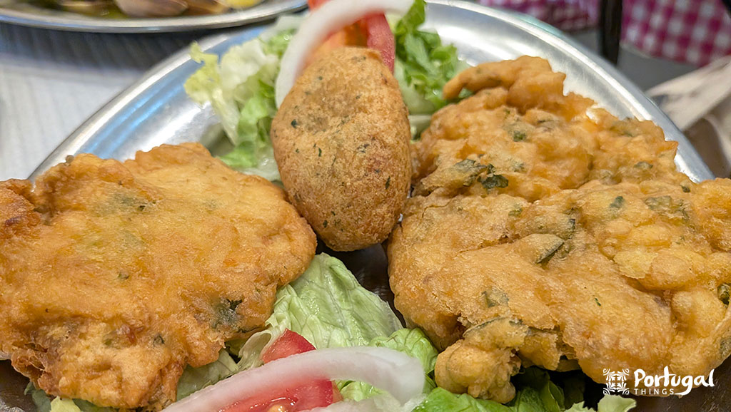 um prato com alface e por cima tem duas pataniscas e um bolinho de bacalhau