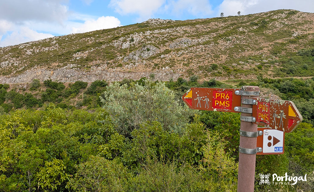 Porto de Mós Ecotrail: Trail, Tunnels, and Windmills 5 Wooden trail marker for the PR6, with a mountain in the background