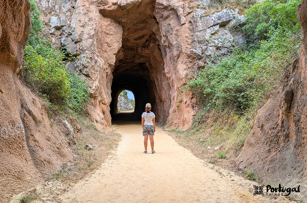 Porto de Mós Ecotrail: Trail, Tunnels, and Windmills 2 Someone standing with their back to the camera in front of a cave in a rocky gorge