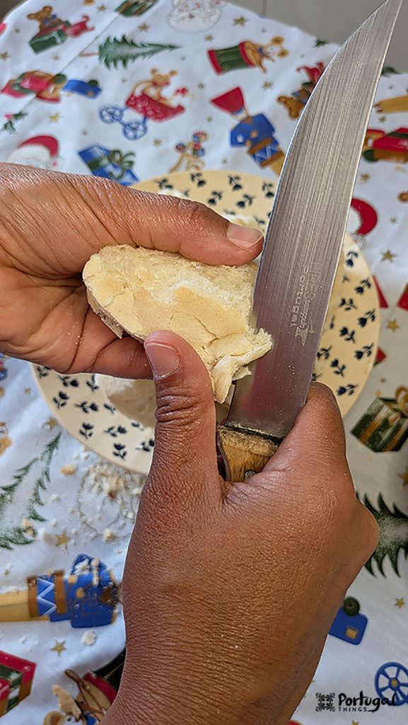 Rabanadas Poveiras – Traditional Portuguese Recipe from Póvoa de Varzim 5 A hand cuts the crust of a loaf of bread with a knife.
