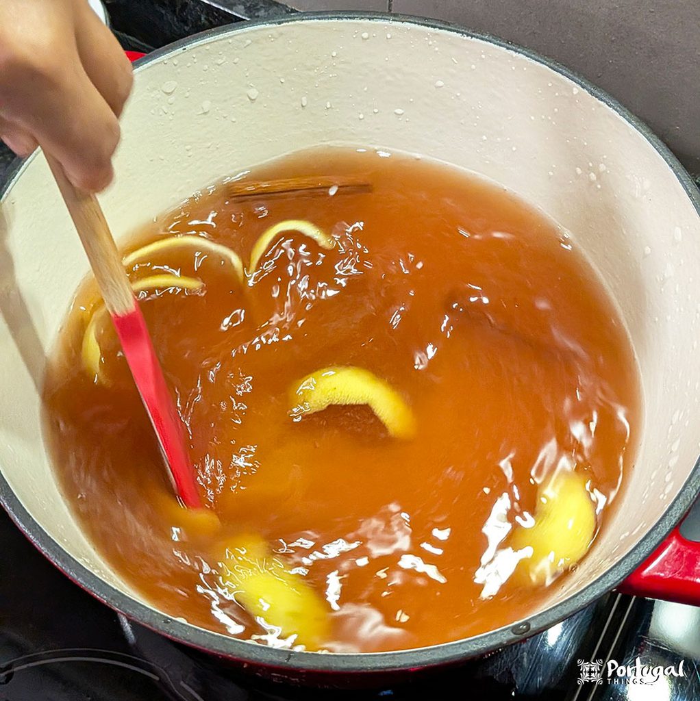 Mexidos: A Traditional Portuguese Christmas Dessert 4 uma mão mexe um tacho com uma calda com cor de Amber e casca de limão